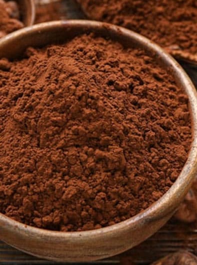 Bowls with cocoa powder and beans on wooden background