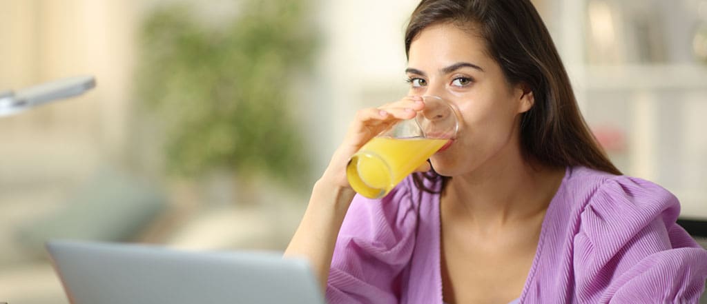 Student drinking orange juice and looking at camera